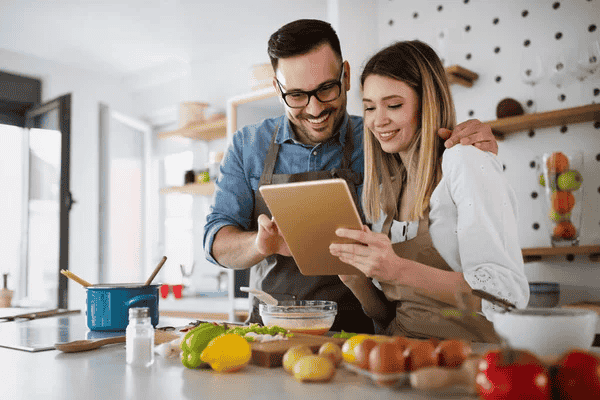 Pareja consultando una tablet en la cocina